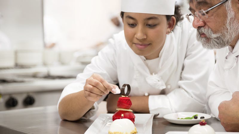 A student chef plating a dessert