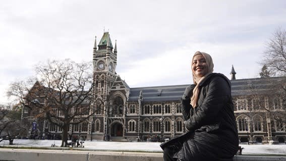Arina sitting in front of the University of Otago clock tower. 